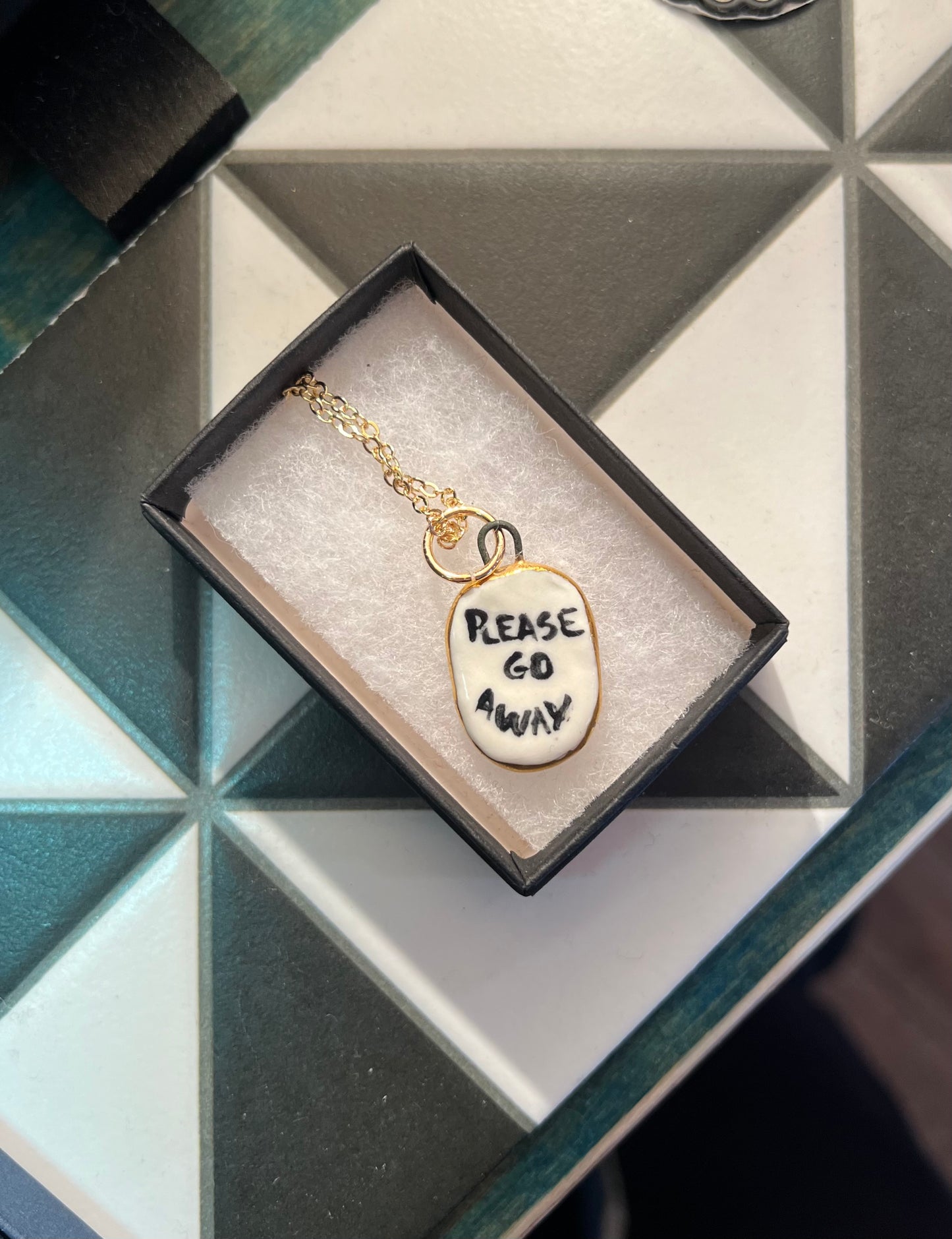 Porcelain oval "Please go Away" pendant with gold rim by REBECCA EDELMANN