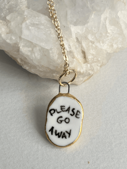 Porcelain oval "Please go Away" pendant with gold rim by REBECCA EDELMANN