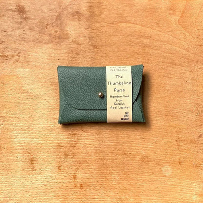 Green leather purse with a label on a wooden surface